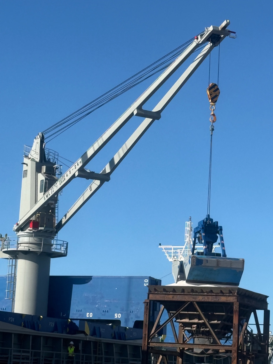 Ship crane operating at GCS Gulf Coast port — bulk cargo operations