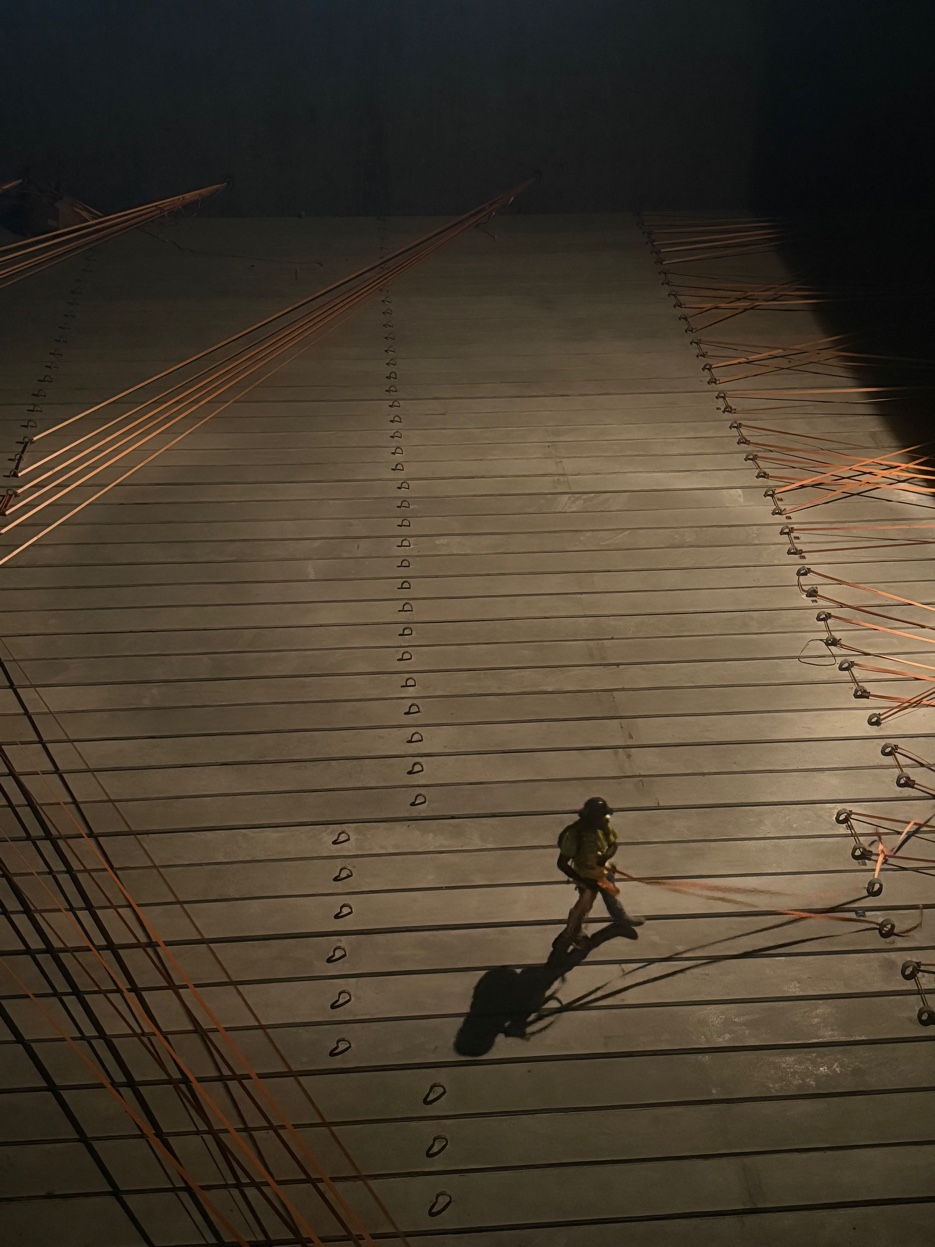 GCS stevedore at night on concrete pile deck — experienced crew member with rigging equipment in active operation